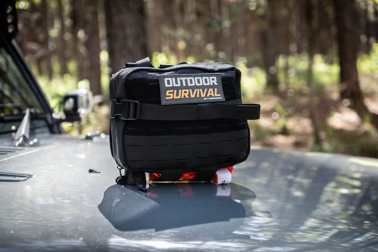 Large Black Survival Kit in Australian bushland with Molle / PALS webbing, velcro patch and combat application tourniquet
