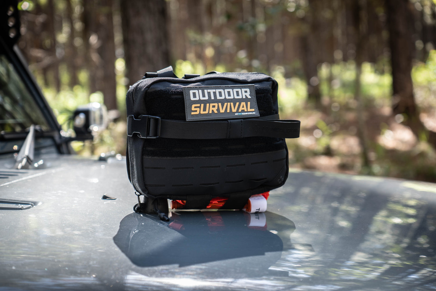 Large Black Survival Kit in Australian bushland with Molle / PALS webbing, velcro patch and combat application tourniquet