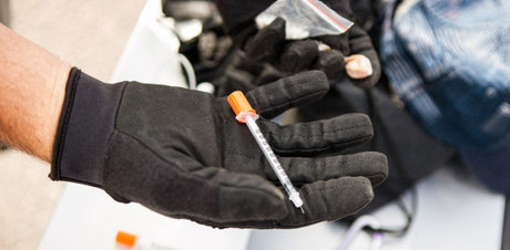 Puncture proof gloves holding hypodermic needle