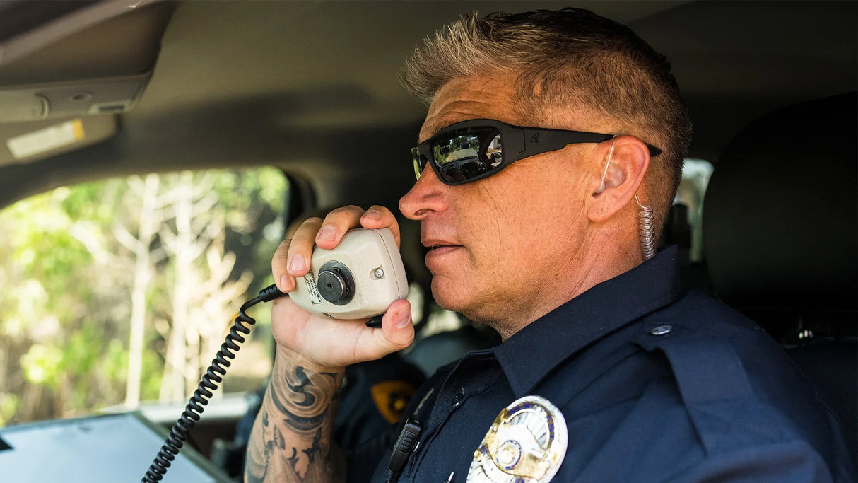 Police officer using vehicle radio wearing ballistic sunglasses