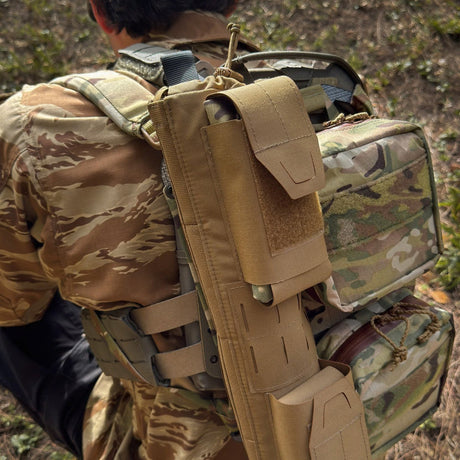 Soldier with camouflage backpack and EVAC Sleeve on back on grass.