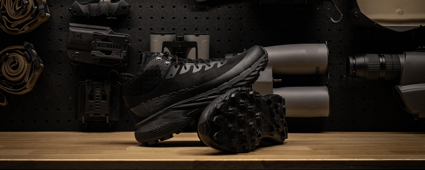 Black Merrell boots on a wooden surface with a pegboard background